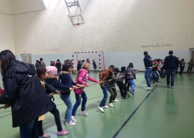 Niños jugando al tira y afloja en gimnasio.