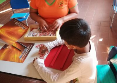 Profesora enseña a niño con materiales educativos.