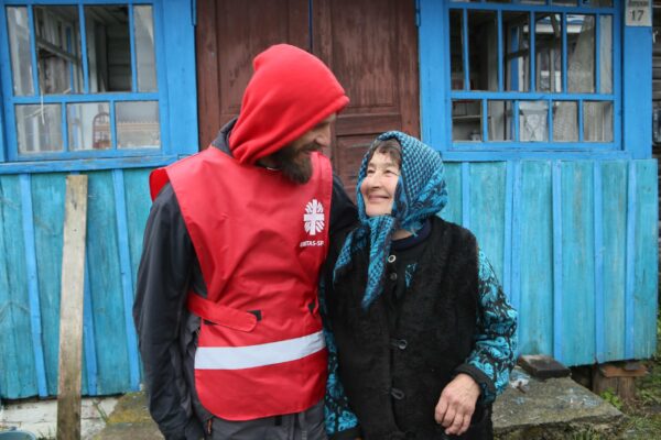 Hombre y mujer sonríen frente a casa azul.