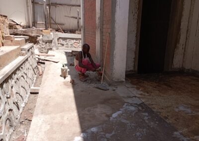 Persona barriendo en construcción bajo el sol