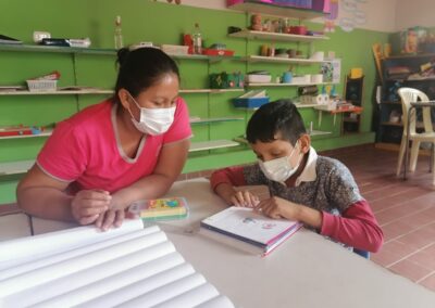 Niño y maestra con mascarillas estudiando juntos.